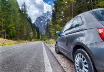Road and car and Alpine mountains on the background.